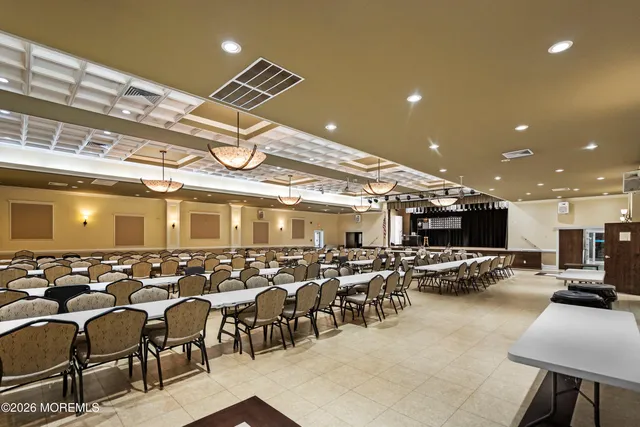 a large dining hall with stainless steel appliances granite countertop a table chairs in it and wooden floor