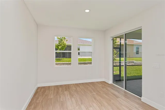 a view of an empty room with wooden floor and windows