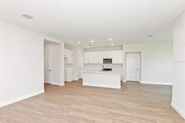 a view of kitchen with kitchen island a sink wooden floor and a refrigerator