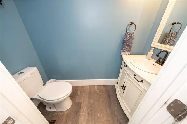 a white toilet sitting next to a sink and a wooden floor
