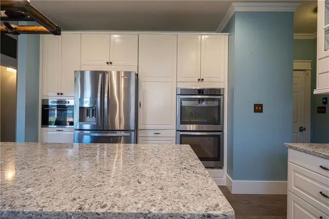 a kitchen with stainless steel appliances kitchen island granite countertop a refrigerator and a stove top oven