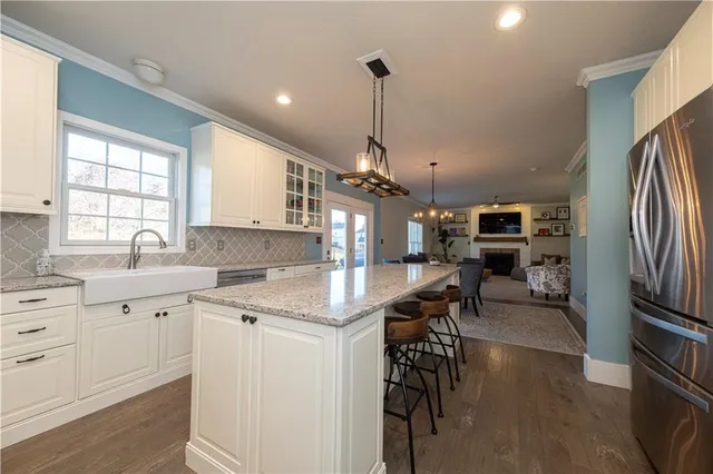 a kitchen with stainless steel appliances granite countertop a stove top oven a sink a dining table and chairs with wooden floor