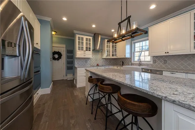 a kitchen with granite countertop a table chairs window and refrigerator