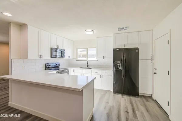 a kitchen with a refrigerator a sink and dishwasher with white cabinets