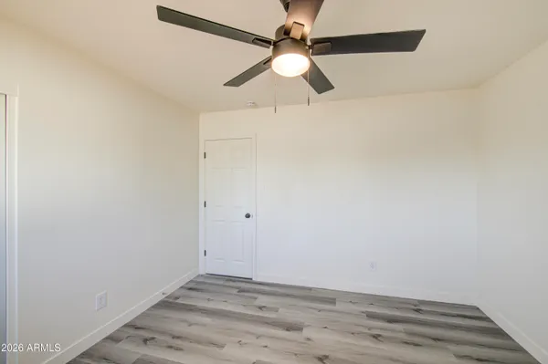 an empty room with wooden floor ceiling fan and window