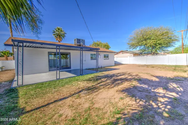 a view of yellow house with a yard and large tree