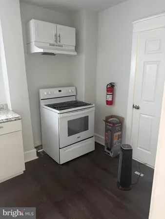 a kitchen with a stove and wooden floor
