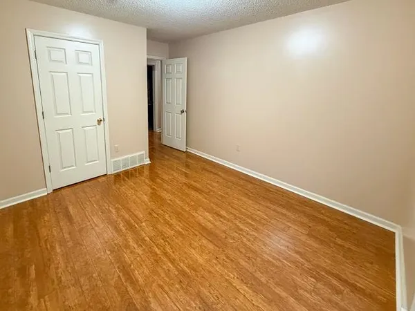 an empty room with wooden floor and closet area