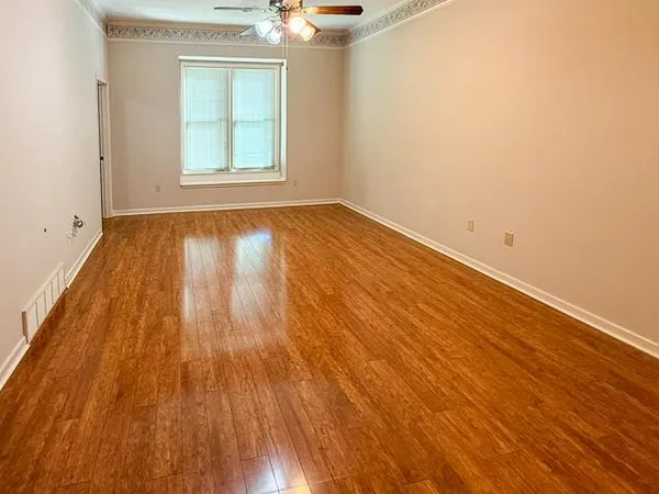 an empty room with wooden floor and windows