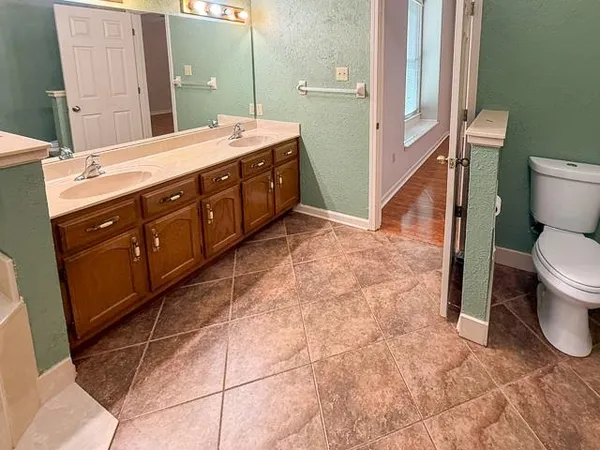 a spacious bathroom with a granite countertop toilet sink and mirror