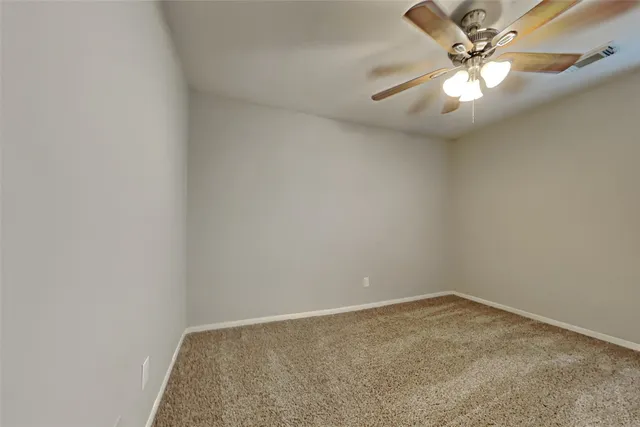 an empty room with a chandelier fan and windows