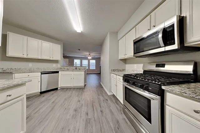 a kitchen with stainless steel appliances white cabinets granite counter tops and a stove