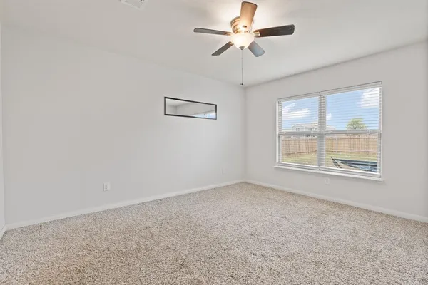 an empty room with a window and a fan