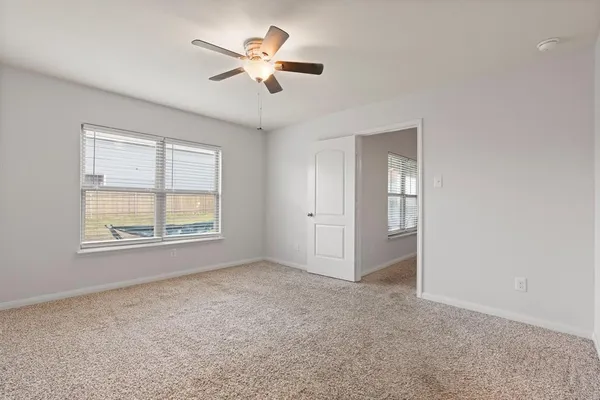 an empty room with windows and ceiling fan