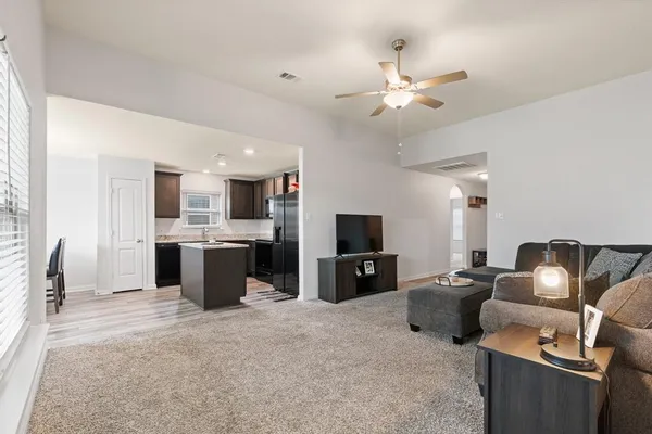 a living room with furniture a flat screen tv and kitchen view