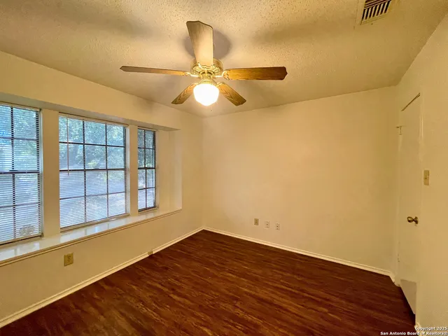 a view of empty room with wooden floor and fan
