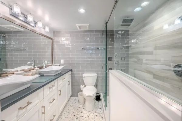 a bathroom with a granite countertop sink a toilet a mirror and shower