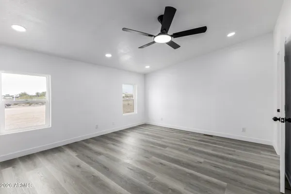 an empty room with wooden floor fan and windows