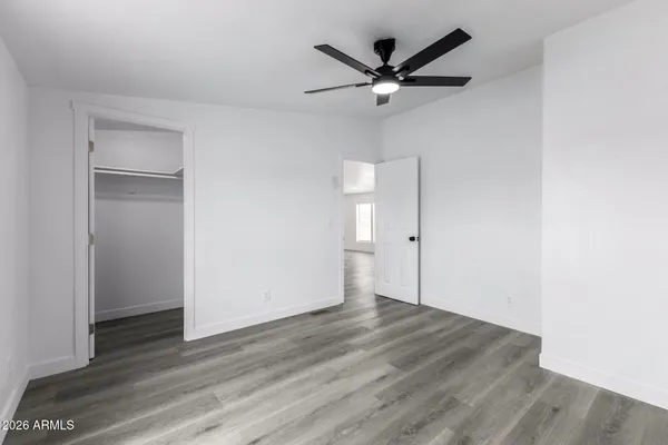 an empty room with wooden floor and a ceiling fan