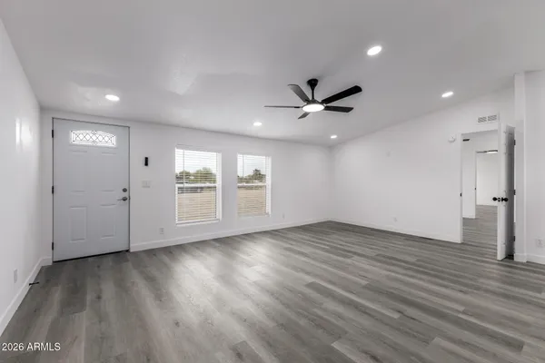 an empty room with wooden floor and windows