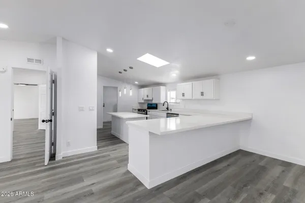 a large white kitchen with wooden floor
