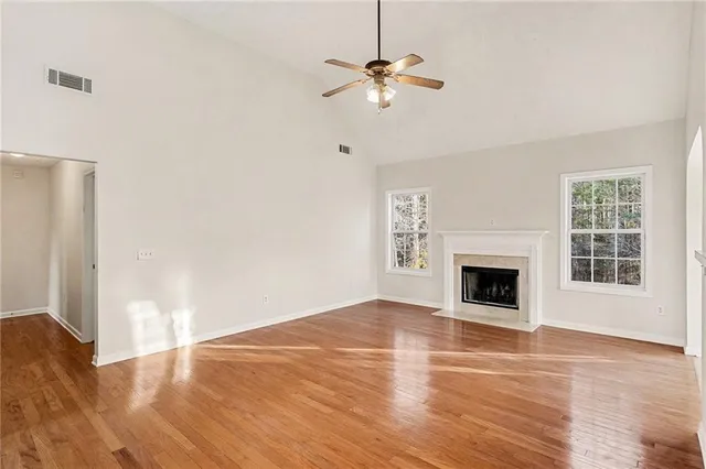 a view of empty room with wooden floor fan and window