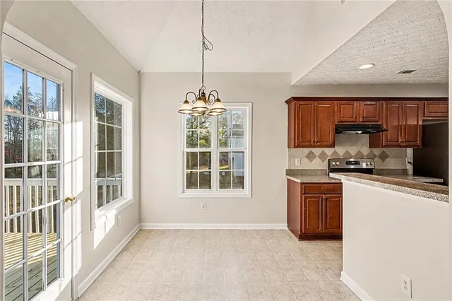 a kitchen with stainless steel appliances granite countertop a stove top oven a refrigerator a sink and dishwasher with a dining table