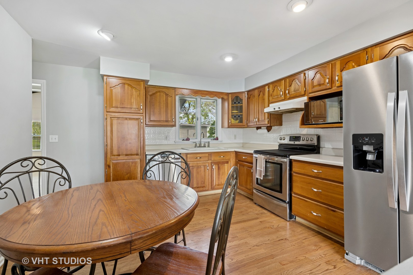 54 Burton Avenue Cary, IL 60013 - Photo 6 of 20 a kitchen with stainless steel appliances granite countertop a sink a stove a dining table and chairs