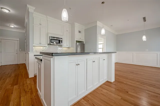 a kitchen with stainless steel appliances granite countertop a refrigerator a sink dishwasher and white cabinets with wooden floor