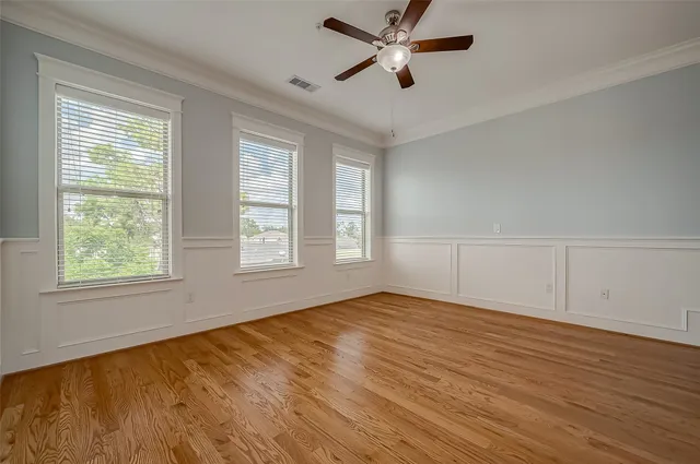 a view of empty room with wooden floor and fan