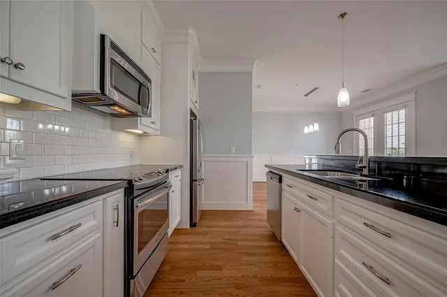 a kitchen with stainless steel appliances granite countertop a sink a stove and a wooden floors