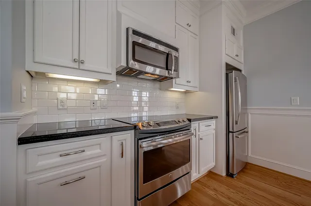 a kitchen with stainless steel appliances granite countertop white cabinets and a stove top oven