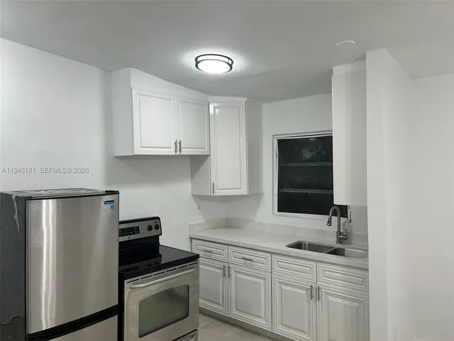 a kitchen with white cabinets sink and stainless steel appliances