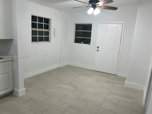 an empty room with windows and fan