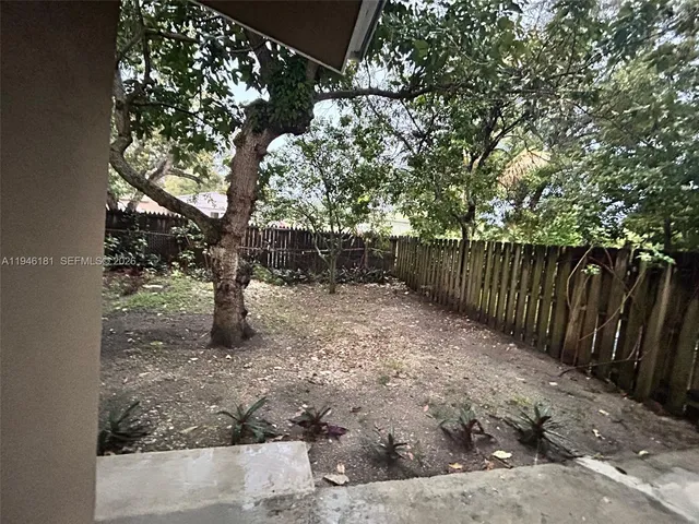 a backyard of a house with table and chairs a fire pit and a large tree