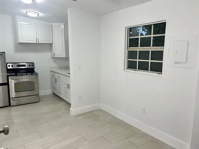 a view of a kitchen with white cabinets and a stove top oven