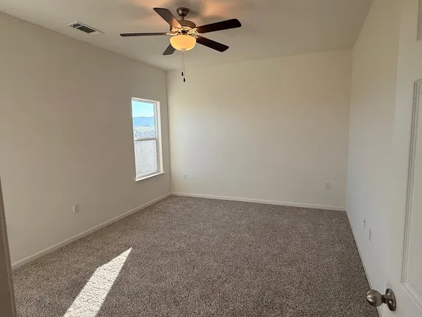 an empty room with windows and fan