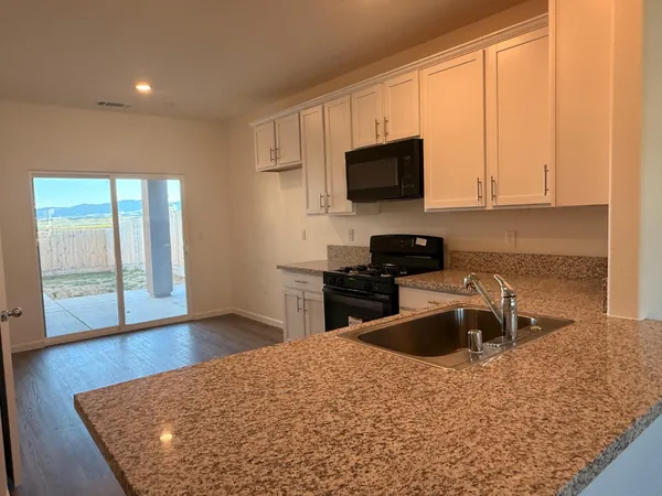 a kitchen with stainless steel appliances granite countertop a sink a stove and a microwave with wooden floor