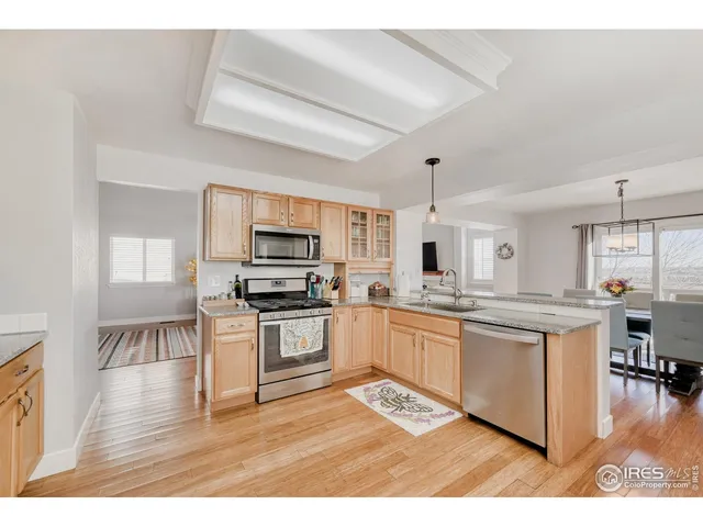 a kitchen with stainless steel appliances granite countertop a stove top oven a sink dishwasher and white cabinets with wooden floor