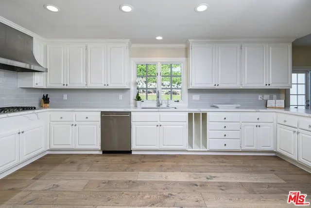 a kitchen with white cabinets white stainless steel appliances and sink