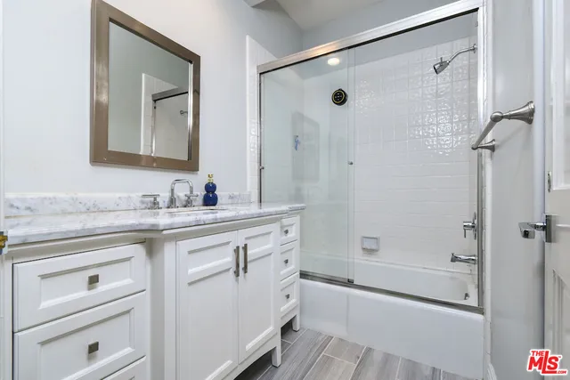 a bathroom with a granite countertop sink a mirror a shower and a bathtub
