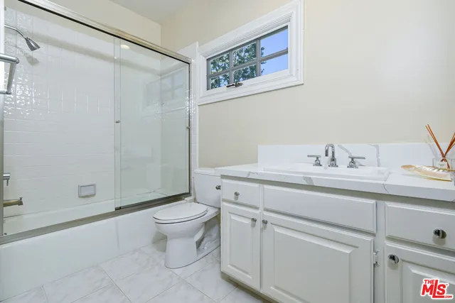 a bathroom with a granite countertop sink a toilet and shower