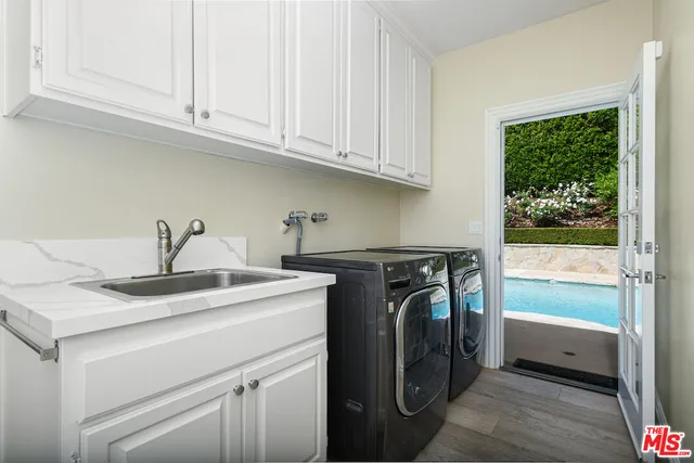 a utility room with stainless steel appliances granite countertop a sink and a washer dryer