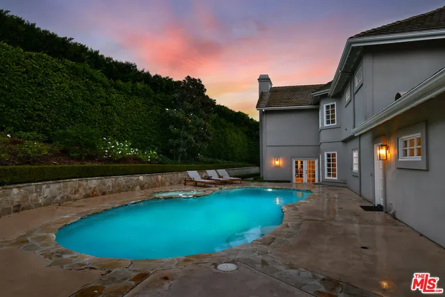 a view of a swimming pool with lawn chairs under an umbrella