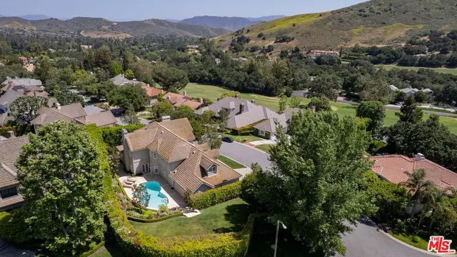 an aerial view of a houses with a street and green space