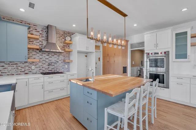 a kitchen with stainless steel appliances kitchen island granite countertop a table chairs sink refrigerator and cabinets