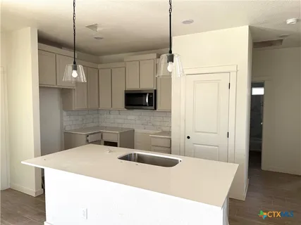 a kitchen with a sink a microwave a refrigerator and white cabinets