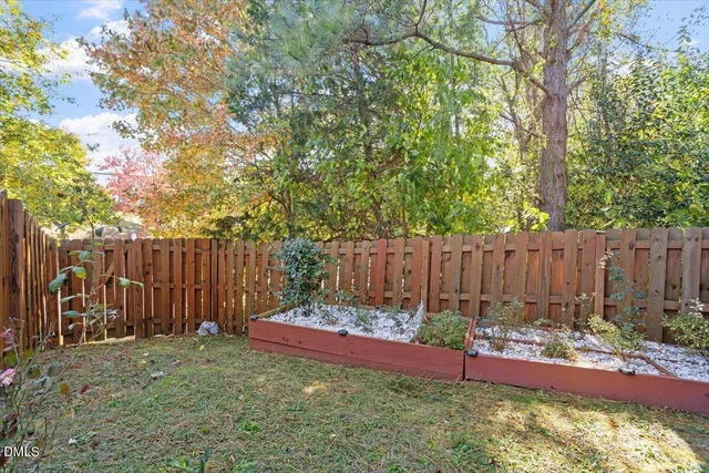 a view of a backyard with a large tree and wooden fence
