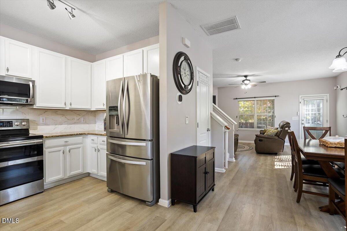 3502 Oneonta Avenue Raleigh, NC 27604 - Photo 9 of 28 a kitchen with stainless steel appliances a refrigerator a stove a sink a dining table and chairs with wooden floor