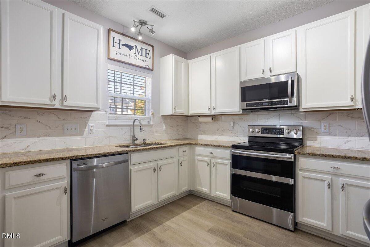 3502 Oneonta Avenue Raleigh, NC 27604 - Photo 10 of 28 a kitchen with stainless steel appliances granite countertop white cabinets granite counter tops and a window